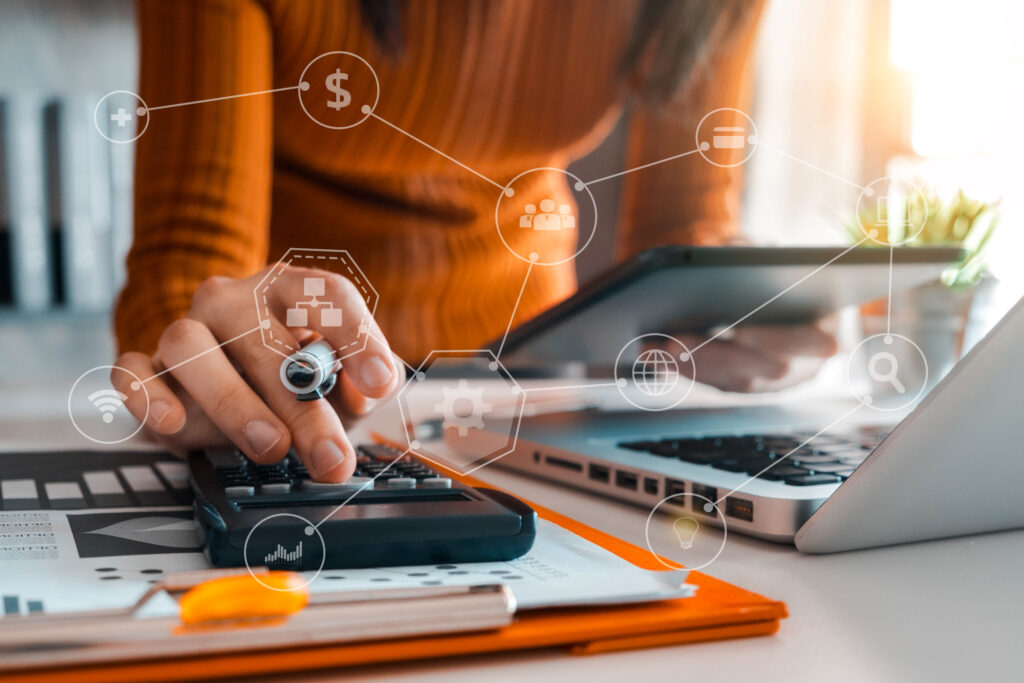 Image of woman with orange sweater woking on a computer with icons to represent money and other functions for service engineering.