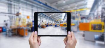 Tablet in front of a manufacturing company with the same image of the company on the tablet as in the background