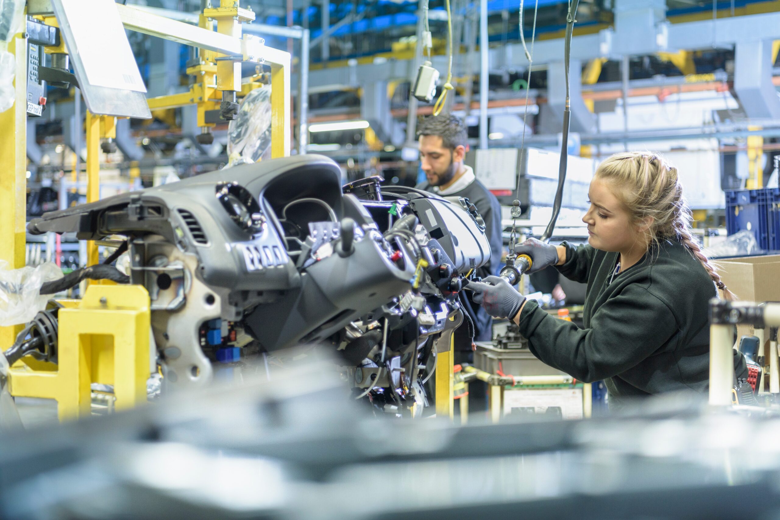 Woman working on a car engine in an automotive manufacting plant