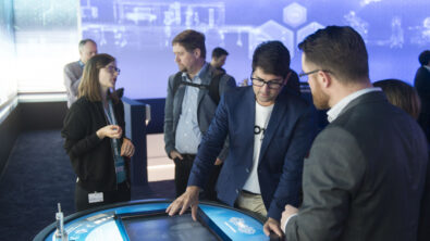 Group standing around a touch screen embedded in a round table