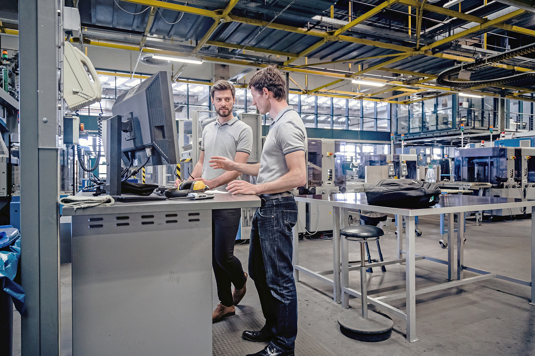 Two men in manufacturing plant standing at a computer