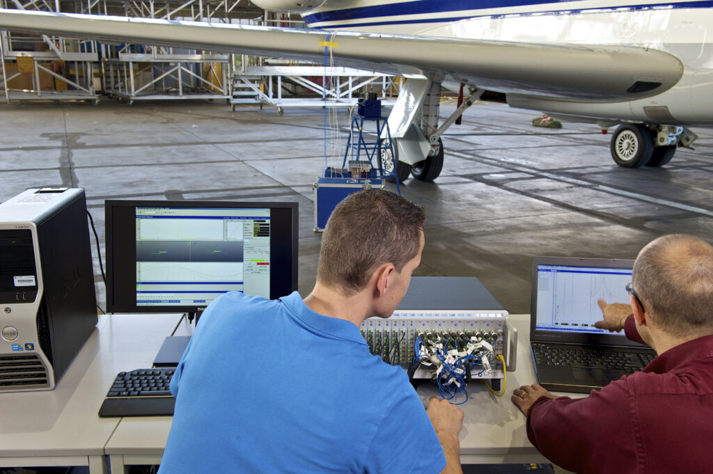 Engineers perform a ground vibration test on an aircraft using modal testing equipment