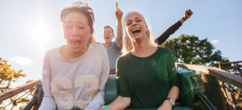 Enthusiastic young friends riding amusement park ride