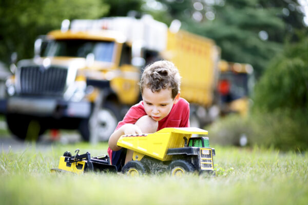 Young boy plays with a toy truck in the garden. The toy seems to withstand all harsh conditions.