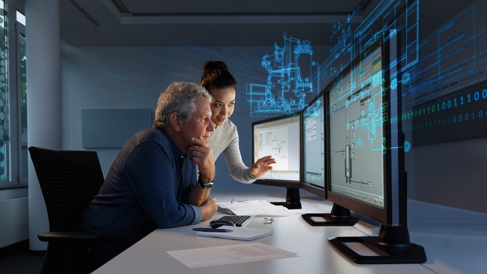 Two engineers examining simulation models on a computer monitor, with a digital overlay of the design symbolizing the digital twin