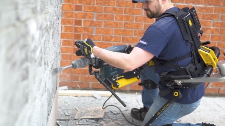 A Freschco.ca worker wears an exoskeleton while using a chipper to clear tiles off a wall. (Freshco.ca/Youtube)