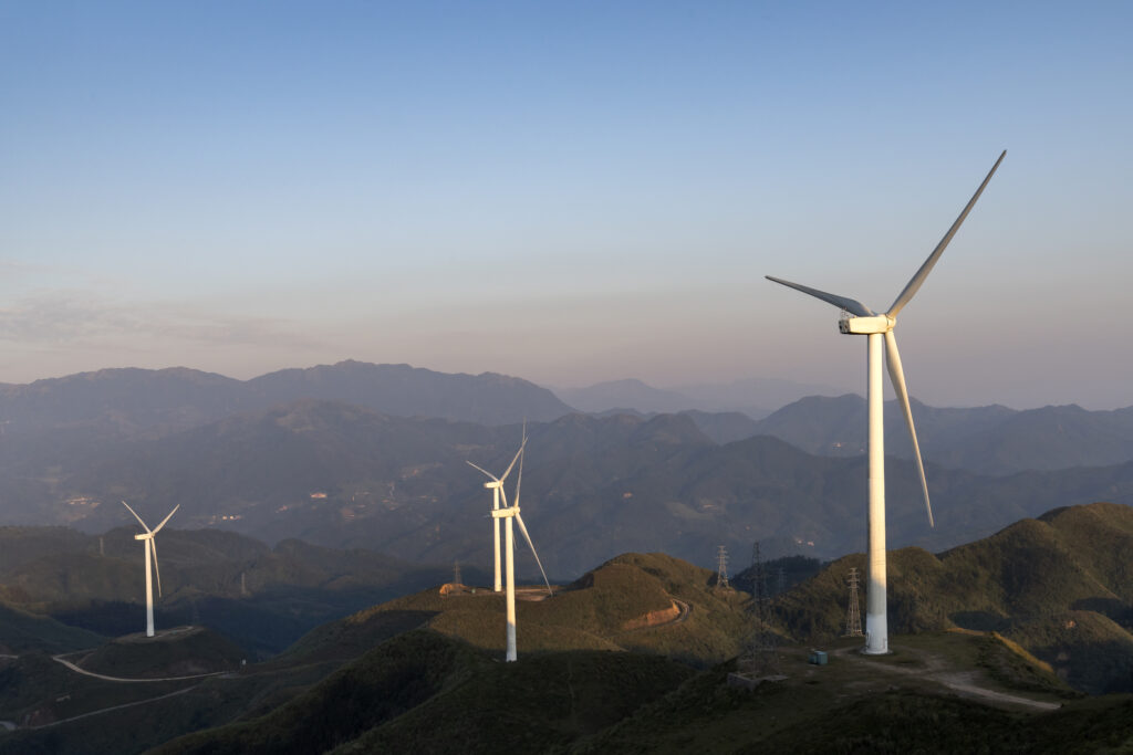 Wind turbines on high mountains set against the sunrise and sunset sky