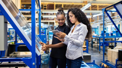 Two women looking at a tablet in a manufacturing setting