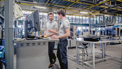 Two men in manufacturing plant standing at a computer