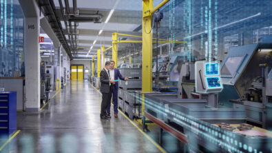 Two men standing in a factory next to machinery