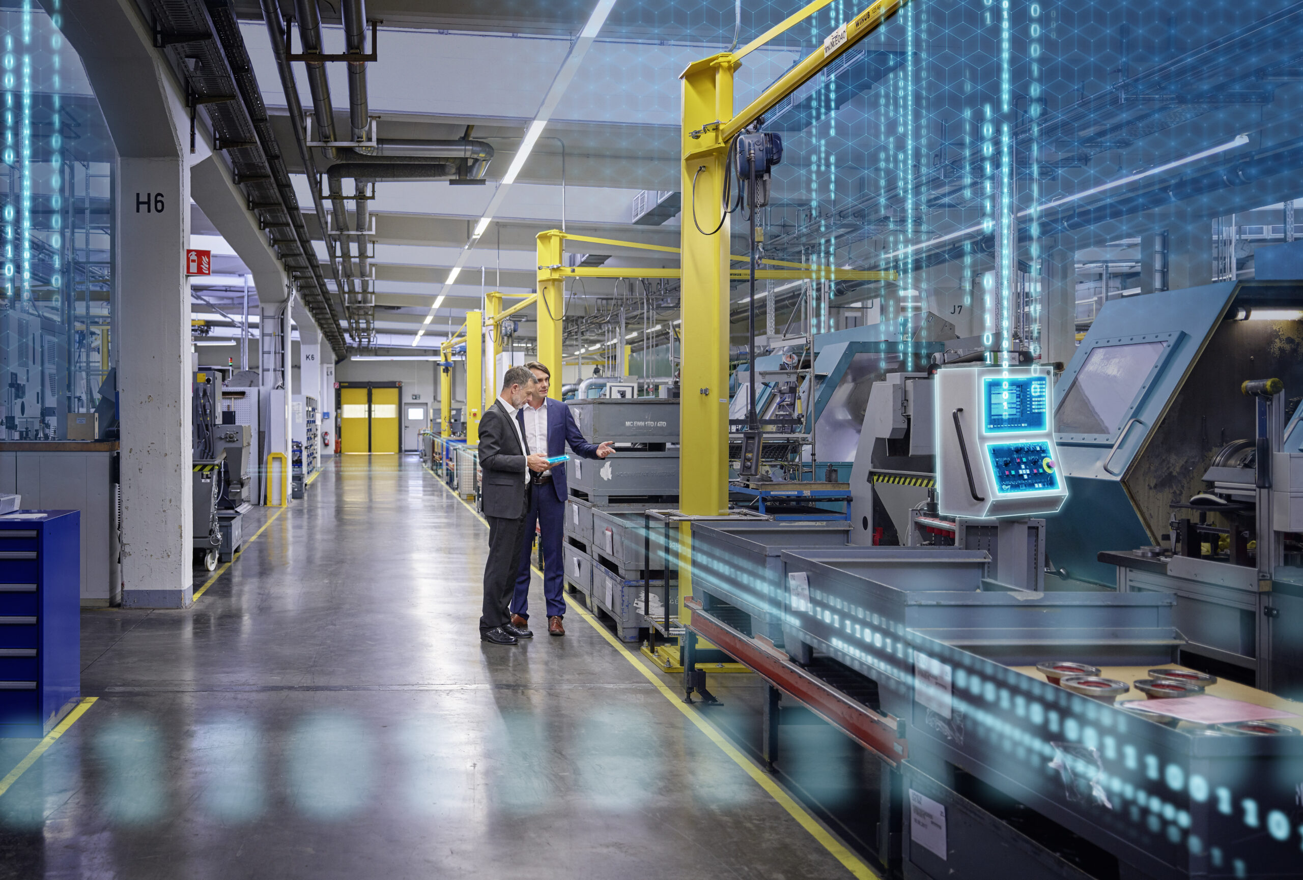 Two men standing in a factory next to machinery