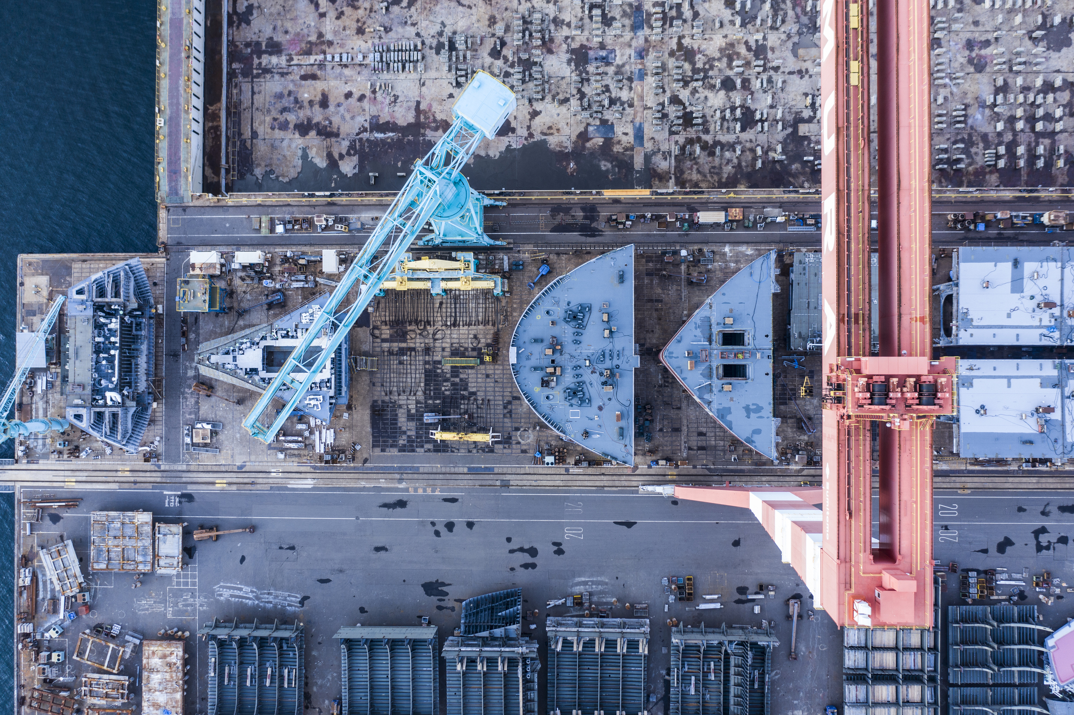 A picture of a ship being built in a shipyard on the beachfront.