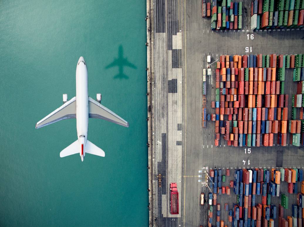 airplane-flying-over-container-port