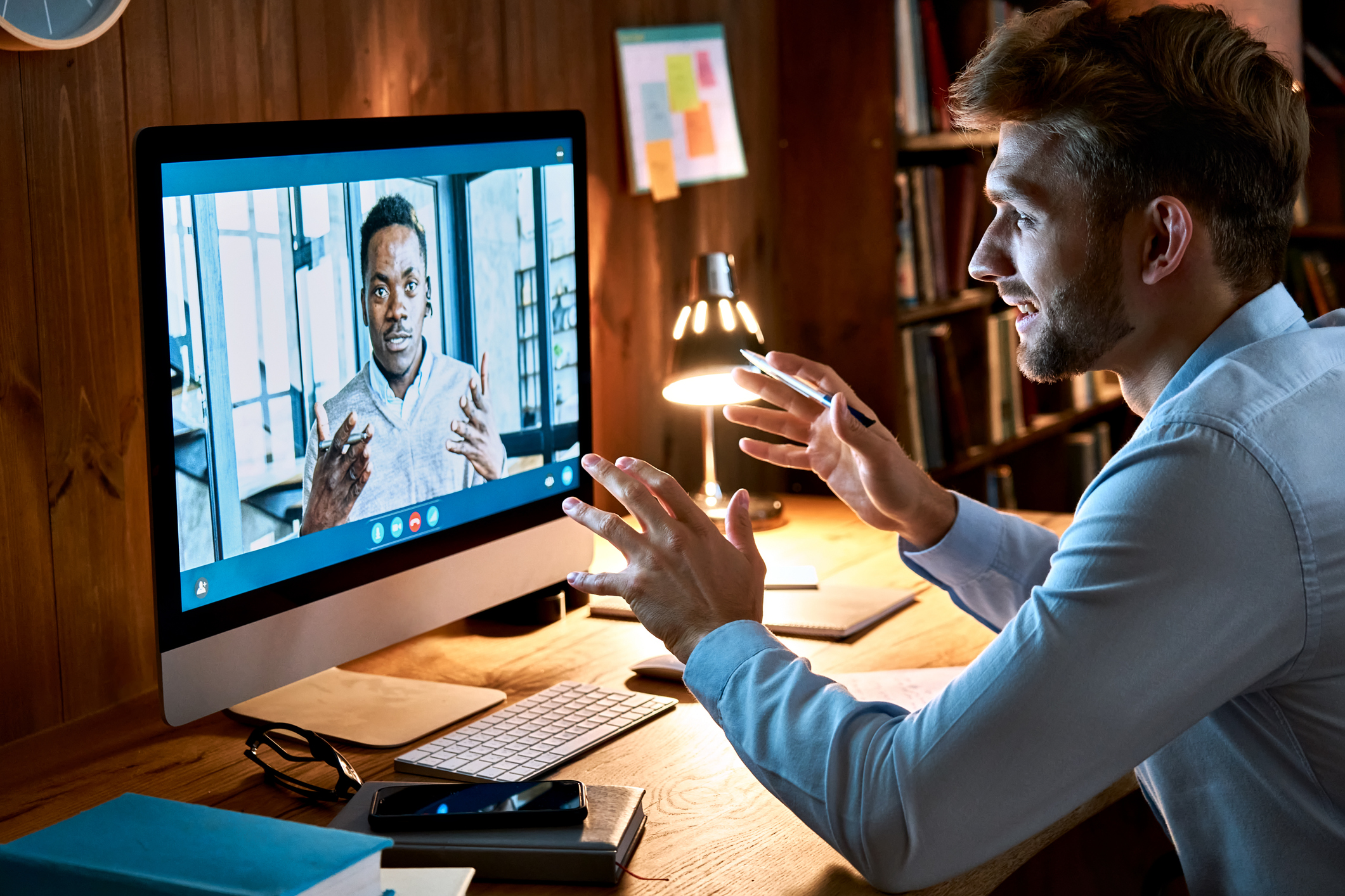 Caucasian business man talking with african male partner coach on video conference call discussing social distance work at virtual remote meeting videoconference chat using pc computer at home office.