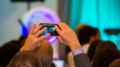 Conference attendee taking a photo on their smartphone above the crowd