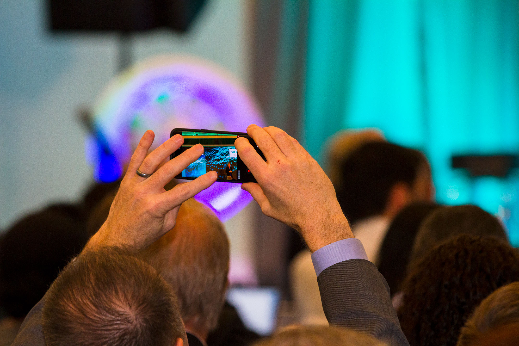 Conference attendee taking a photo on their smartphone above the crowd