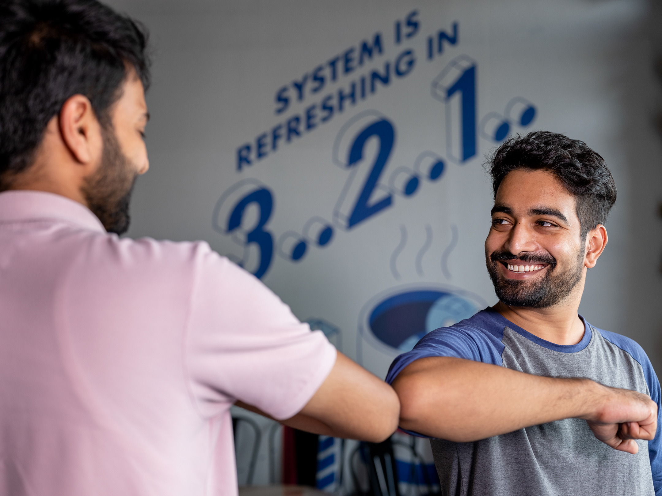 Indian man bumping elbows with his colleague in the office