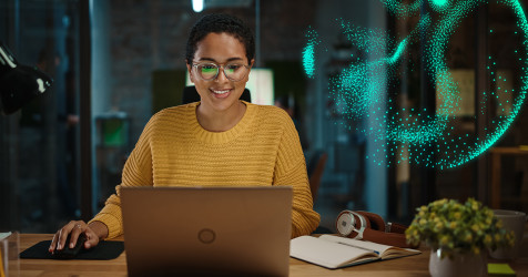 Woman working on a laptop using cloud solutions, overlayed with digital superimposition particle effect